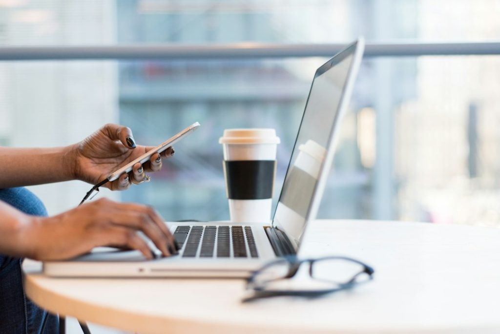 Seseorang menggunakan smartphone dan laptop untuk aktivitas digital