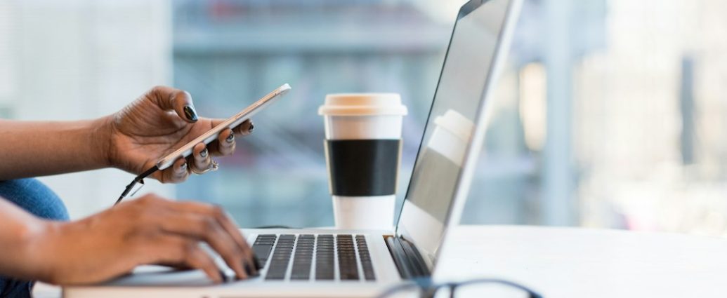 Seseorang menggunakan smartphone dan laptop untuk aktivitas digital