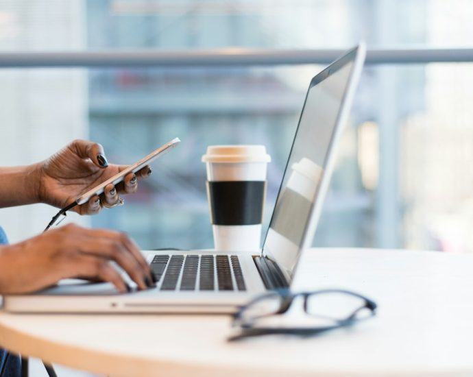 Seseorang menggunakan smartphone dan laptop untuk aktivitas digital